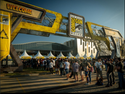Crowd entering the San Diego Comic Con Malaga through a large yellow welcome archway outside the event venue.